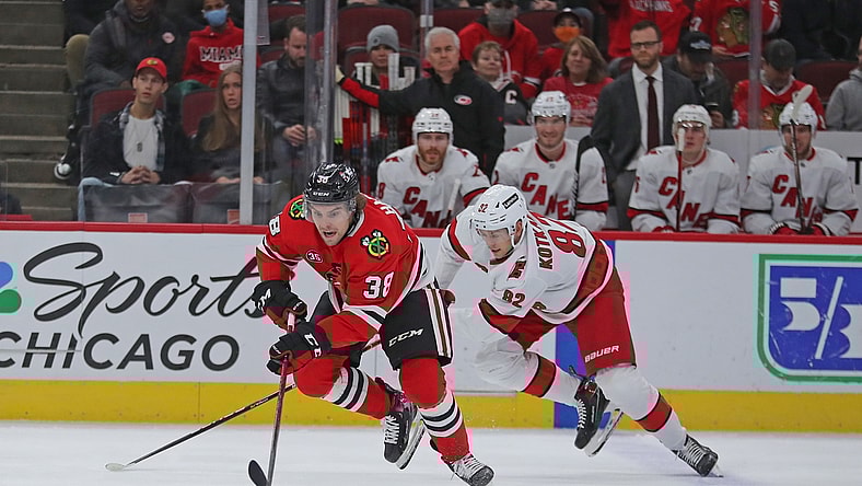 Nov 3, 2021; Chicago, Illinois, USA; Chicago Blackhawks left wing Brandon Hagel (38) and Carolina Hurricanes center Jesperi Kotkaniemi (82) chase the puck during the first period at the United Center. Mandatory Credit: Dennis Wierzbicki-USA TODAY Sports
