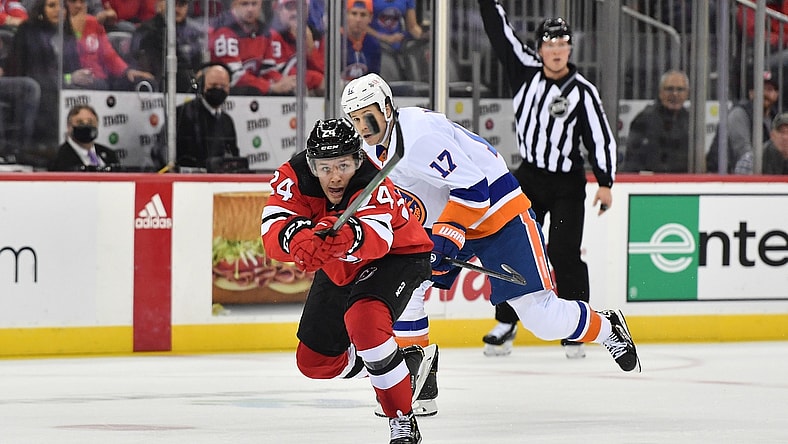 Nov 11, 2021; Newark, New Jersey, USA; New Jersey Devils defenseman Ty Smith (24) deflects the puck against New York Islanders left wing Matt Martin (17) during the second period at Prudential Center. Mandatory Credit: Catalina Fragoso-USA TODAY Sports