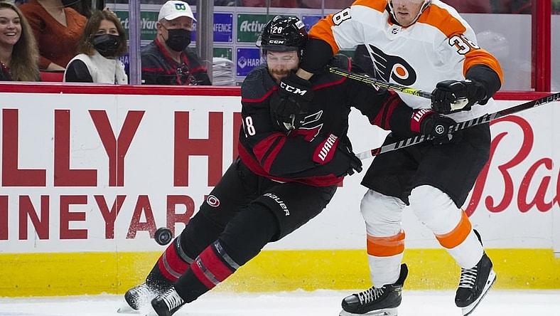 Nov 12, 2021; Raleigh, North Carolina, USA;  Philadelphia Flyers center Patrick Brown (38) and Carolina Hurricanes defenseman Ian Cole (28) chase after the puck during the first period at PNC Arena. Mandatory Credit: James Guillory-USA TODAY Sports