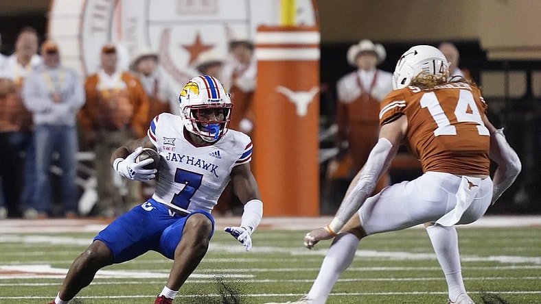 Nov 13, 2021; Austin, Texas, USA; Kansas Jayhawks running back Keilan Robinson (7) tries to avoid a tackle by Texas Longhorns defensive back Brenden Schooler (14) during the first half at Darrell K Royal-Texas Memorial Stadium. Mandatory Credit: Scott Wachter-USA TODAY Sports