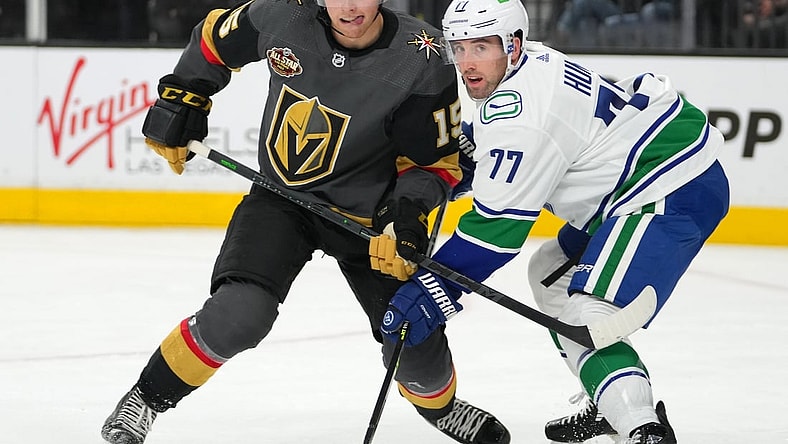 Nov 13, 2021; Las Vegas, Nevada, USA; Vegas Golden Knights center Jake Leschyshyn (15) ties up the stick of Vancouver Canucks defenseman Brad Hunt (77) during the second period at T-Mobile Arena. Mandatory Credit: Stephen R. Sylvanie-USA TODAY Sports