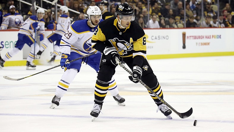 Nov 16, 2021; Pittsburgh, Pennsylvania, USA;  Pittsburgh Penguins defenseman Brian Dumoulin (8) handles the puck  as Buffalo Sabres left wing Vinnie Hinostroza (29) chases during the first period at PPG Paints Arena. Mandatory Credit: Charles LeClaire-USA TODAY Sports