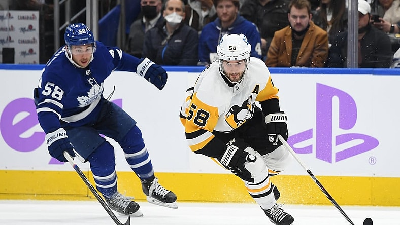 Nov 20, 2021; Toronto, Ontario, CAN;   Pittsburgh Penguins defenseman Kris Letang (58) pursues a loose puck ahead of Toronto Maple Leafs forward Michael Bunting (58) in the second period at Scotiabank Arena. Mandatory Credit: Dan Hamilton-USA TODAY Sports