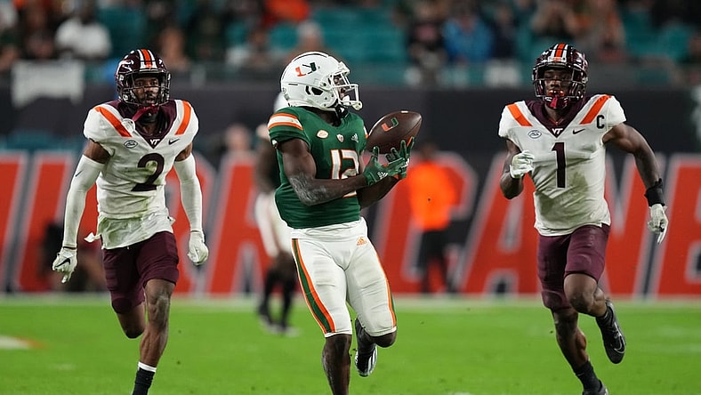 Nov 20, 2021; Miami Gardens, Florida, USA; Miami Hurricanes wide receiver Brashard Smith (12) makes a catch in front of Virginia Tech Hokies defensive back Jermaine Waller (2) and defensive back Chamarri Conner (1) before running for a touchdown in the first half at Hard Rock Stadium. Mandatory Credit: Jasen Vinlove-USA TODAY Sports