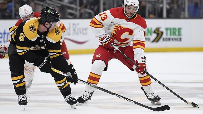 Nov 21, 2021; Boston, Massachusetts, USA;  Calgary Flames left wing Johnny Gaudreau (13) controls the puck while Boston Bruins defenseman Mike Reilly (6) defends during the second period at TD Garden. Mandatory Credit: Bob DeChiara-USA TODAY Sports