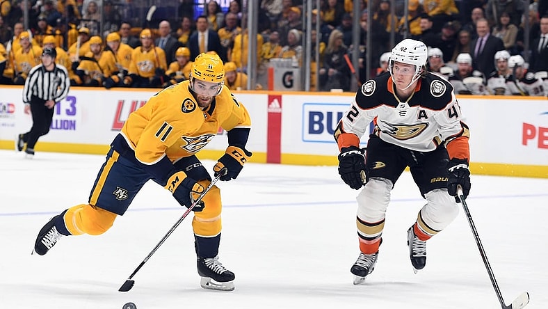 Nov 22, 2021; Nashville, Tennessee, USA; Nashville Predators center Luke Kunin (11) skates with the puck before pressure from Anaheim Ducks defenseman Josh Manson (42) during the first period at Bridgestone Arena. Mandatory Credit: Christopher Hanewinckel-USA TODAY Sports