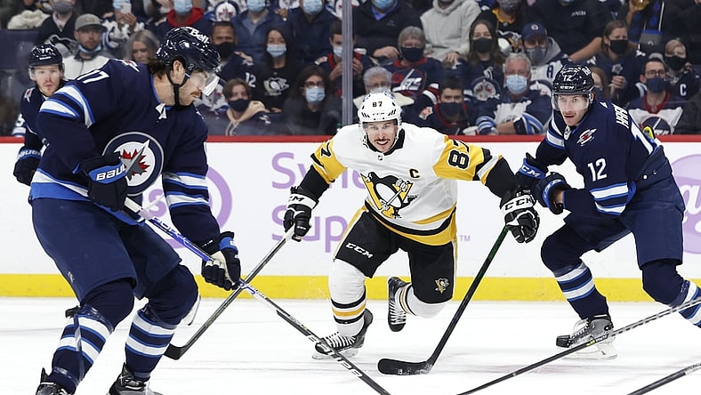 Nov 22, 2021; Winnipeg, Manitoba, CAN; Pittsburgh Penguins center Sidney Crosby (87) and Winnipeg Jets center Jansen Harkins (12) chase down the puck controlled by left wing Adam Lowry (17) in the first period at Canada Life Centre. Mandatory Credit: James Carey Lauder-USA TODAY Sports