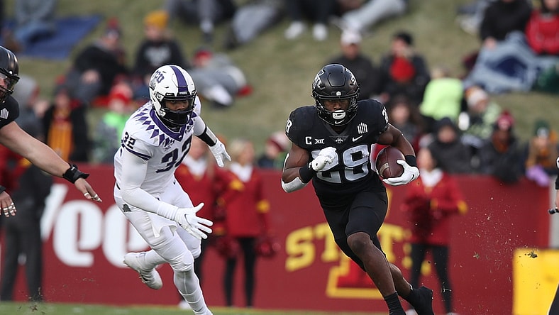 Nov 26, 2021; Ames, Iowa, USA; Iowa State Cyclones running back Breece Hall (28) runs away from TCU Horned Frogs defensive end Ochaun Mathis (32) at Jack Trice Stadium. Mandatory Credit: Reese Strickland-USA TODAY Sports
