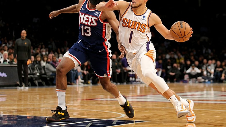 Nov 27, 2021; Brooklyn, New York, USA; Phoenix Suns guard Devin Booker (1) drives to the basket around Brooklyn Nets guard James Harden (13) during the first quarter at Barclays Center. Mandatory Credit: Brad Penner-USA TODAY Sports
