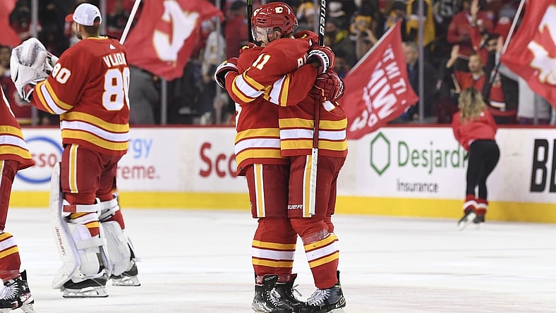 Nov 29, 2021; Calgary, Alberta, CAN; Calgary Flames defenseman Oliver Kylington (58) and forward Mikael Backlund (11) celebrate beating the Pittsburgh Penguins at Scotiabank Saddledome. Flames won 2-1 in a shootout. Mandatory Credit: Candice Ward-USA TODAY Sports