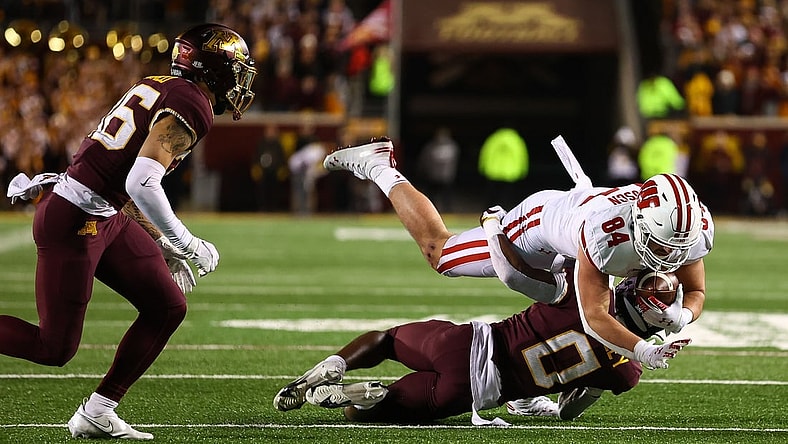 Nov 27, 2021; Minneapolis, Minnesota, USA; Wisconsin Badgers tight end Jake Ferguson (84) runs the ball as Minnesota Gophers defensive back Justin Walley (0) tackles him during the fourth quarter  at Huntington Bank Stadium. Mandatory Credit: Harrison Barden-USA TODAY Sports