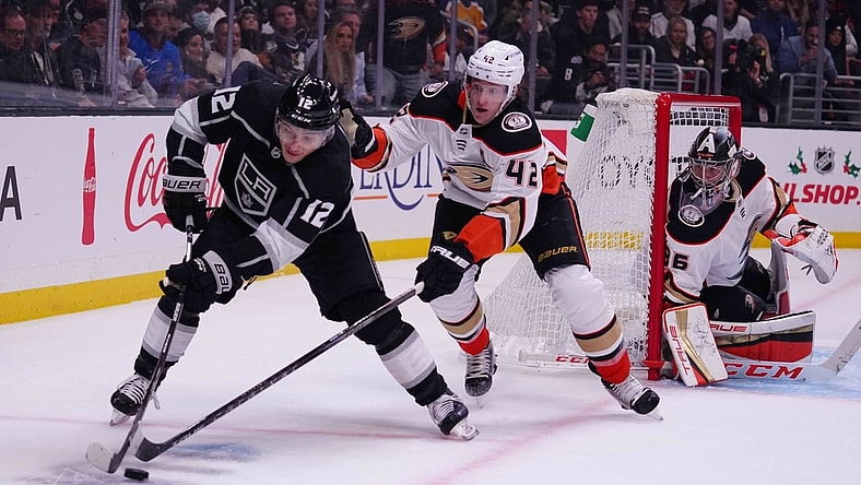 Nov 30, 2021; Los Angeles, California, USA; LA Kings center Trevor Moore (12) and Anaheim Ducks defenseman Josh Manson (42) battle for the puck as Ducks goaltender John Gibson (36) watches in the second period at Staples Center. Mandatory Credit: Kirby Lee-USA TODAY Sports