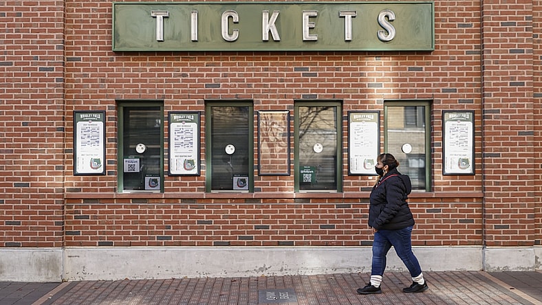 Dec 2, 2021; Chicago, IL, USA; A woman walks by locked Wrigley Field on the first day of Major League Baseball lockout. Mandatory Credit: Kamil Krzaczynski-USA TODAY Sports