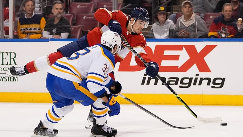 Dec 2, 2021; Sunrise, Florida, USA; Florida Panthers left wing Frank Vatrano (77) shoots the puck in front of Buffalo Sabres defenseman Colin Miller (33) during the second period at FLA Live Arena. Mandatory Credit: Jasen Vinlove-USA TODAY Sports
