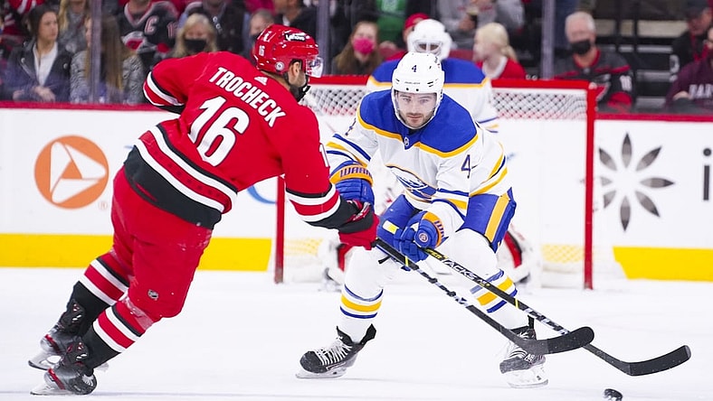 Dec 4, 2021; Raleigh, North Carolina, USA;  Buffalo Sabres defenseman Will Butcher (4) defends against Carolina Hurricanes center Vincent Trocheck (16) during the first period at PNC Arena. Mandatory Credit: James Guillory-USA TODAY Sports