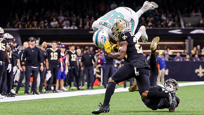 Dec 27, 2021; New Orleans, Louisiana, USA; Miami Dolphins tight end Mike Gesicki (88) leaps over New Orleans Saints cornerback Paulson Adebo (right) during the first half at Caesars Superdome. Mandatory Credit: Stephen Lew-USA TODAY Sports