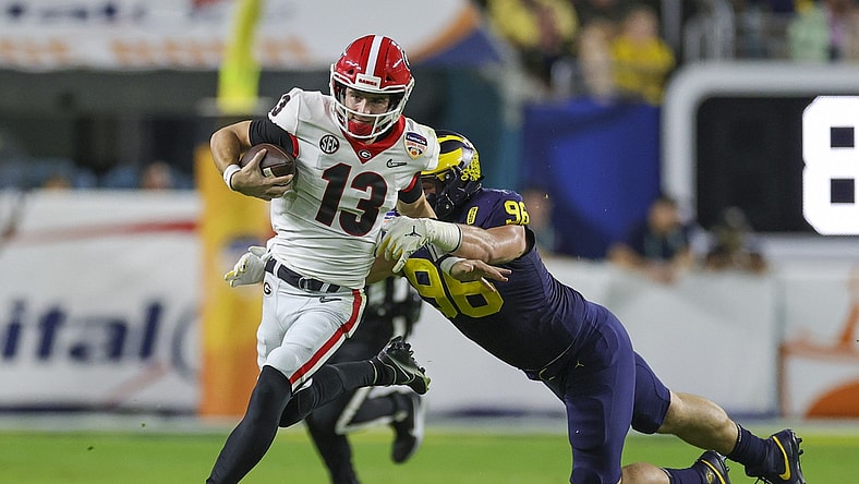 Dec 31, 2021; Miami Gardens, Florida, USA; Georgia Bulldogs quarterback Stetson Bennett (13) runs with the ball ahead of Michigan Wolverines defensive lineman Julius Welschof (96) in the second quarter during the Orange Bowl college football CFP national semifinal game at Hard Rock Stadium. Mandatory Credit: Sam Navarro-USA TODAY Sports