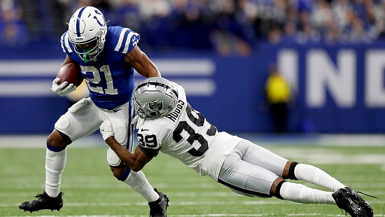 Indianapolis Colts running back Nyheim Hines (21) pushes off of Las Vegas Raiders cornerback Nate Hobbs (39) while rushing the ball Sunday, Jan. 2, 2022, during a game at Lucas Oil Stadium in Indianapolis.