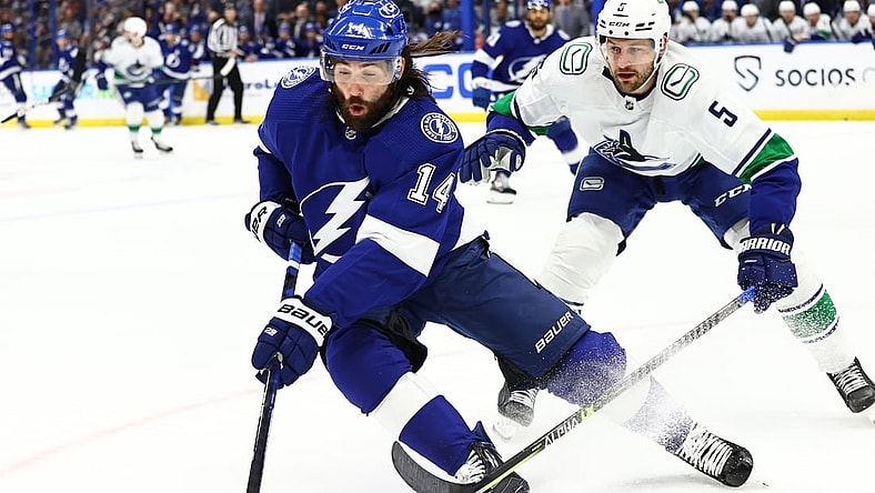 Jan 13, 2022; Tampa, Florida, USA; Tampa Bay Lightning left wing Pat Maroon (14) and Vancouver Canucks defenseman Tucker Poolman (5) skate to control the puck during the first period at Amalie Arena. Mandatory Credit: Kim Klement-USA TODAY Sports
