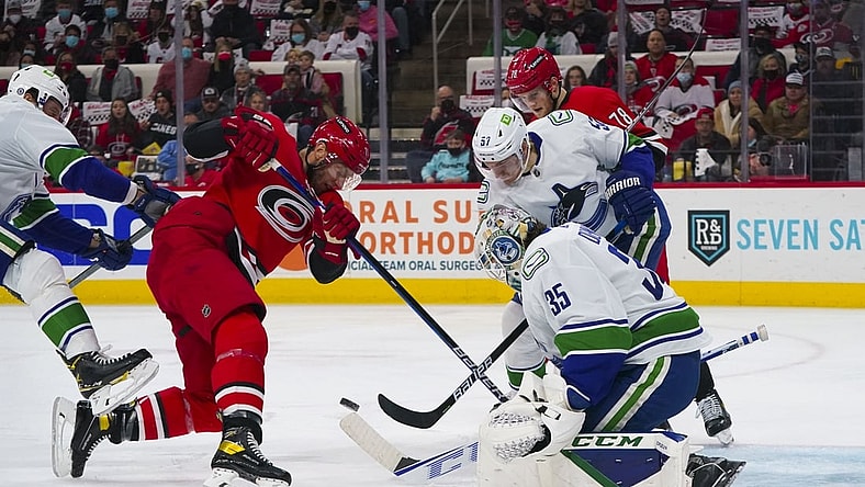 Jan 15, 2022; Raleigh, North Carolina, USA;  Carolina Hurricanes center Jordan Staal (11) and center Steven Lorentz (78) battle over the puck against Vancouver Canucks goaltender Thatcher Demko (35) and defenseman Tyler Myers (57) during the first period at PNC Arena. Mandatory Credit: James Guillory-USA TODAY Sports