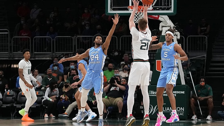 Jan 18, 2022; Coral Gables, Florida, USA; Miami Hurricanes forward Sam Waardenburg (21) attempts a three point shot over North Carolina Tar Heels guard Kerwin Walton (24) during the first half at Watsco Center. Mandatory Credit: Jasen Vinlove-USA TODAY Sports