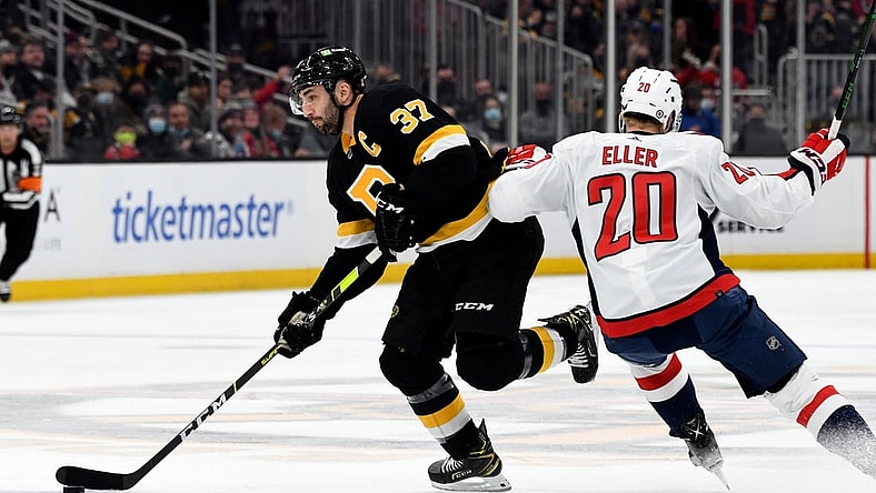 Jan 20, 2022; Boston, Massachusetts, USA; Boston Bruins center Patrice Bergeron (37) skates with the puck across the blue line in front of Washington Capitals center Lars Eller (20) during the first period at the TD Garden. Mandatory Credit: Brian Fluharty-USA TODAY Sports