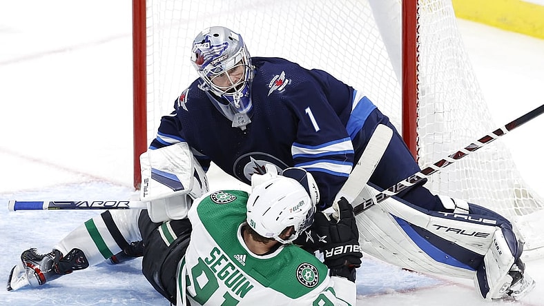 Nov 2, 2021; Winnipeg, Manitoba, CAN;  Dallas Stars center Tyler Seguin (91) collides with Winnipeg Jets goaltender Eric Comrie (1) in the third period at Canada Life Centre. Mandatory Credit: James Carey Lauder-USA TODAY Sports