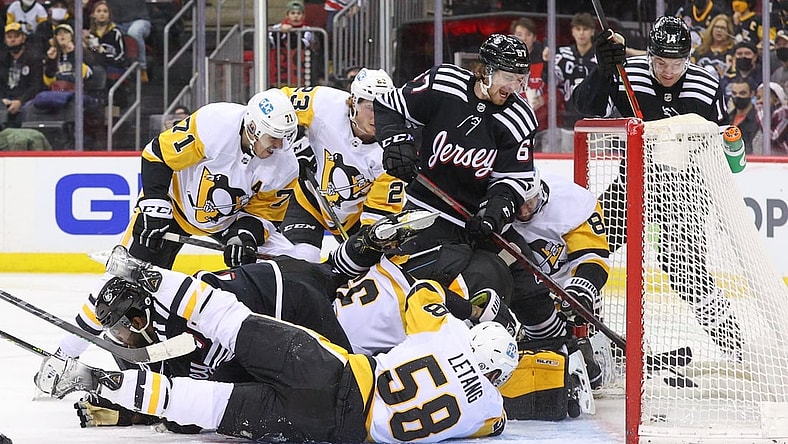 Feb 13, 2022; Newark, New Jersey, USA; Players from the New Jersey Devils and the Pittsburgh Penguins crash the net as the puck goes in during the second period at Prudential Center. The goal was disallowed. Mandatory Credit: Ed Mulholland-USA TODAY Sports
