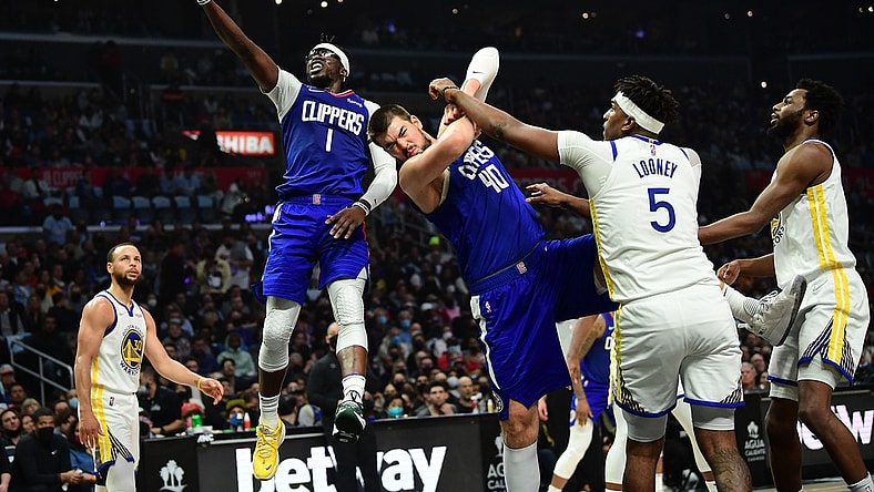Feb 14, 2022; Los Angeles, California, USA; Los Angeles Clippers guard Reggie Jackson (1) moves to the basket as center Ivica Zubac (40) provides coverage against Golden State Warriors center Kevon Looney (5) during the first half at Crypto.com Arena. Mandatory Credit: Gary A. Vasquez-USA TODAY Sports