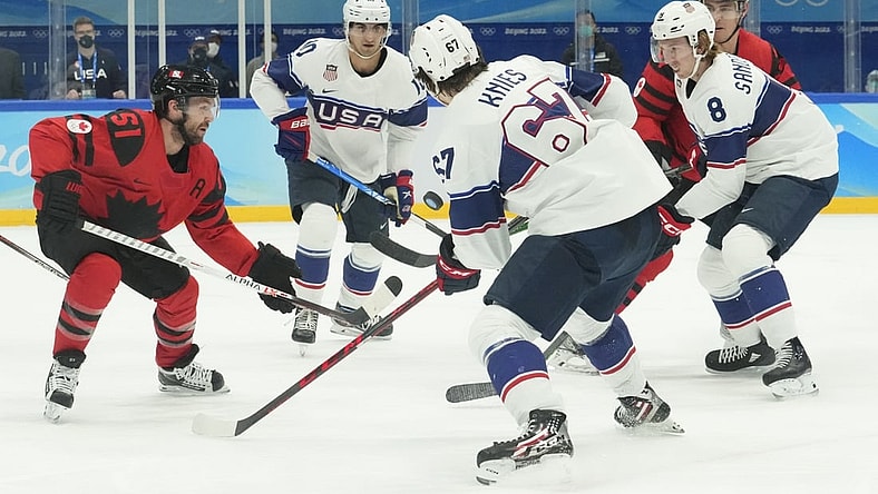Feb 12, 2022; Beijing, China; Team Canada forward David Desharnais (51) fights for the puck with Team USA forward Matty Beniers (10), forward Matt Knies (67), and defender Jake Sanderson (8) during the first period in the men's ice hockey preliminary round of the Beijing 2022 Olympic Winter Games at National Indoor Stadium. Mandatory Credit: Rob Schumacher-USA TODAY Sports
