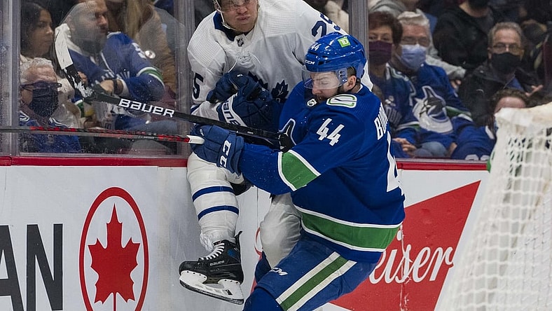 Feb 12, 2022; Vancouver, British Columbia, CAN; Vancouver Canucks defenseman Kyle Burroughs (44) checks Toronto Maple Leafs forward Ondrej Kase (25) in the second period at Rogers Arena. Mandatory Credit: Bob Frid-USA TODAY Sports