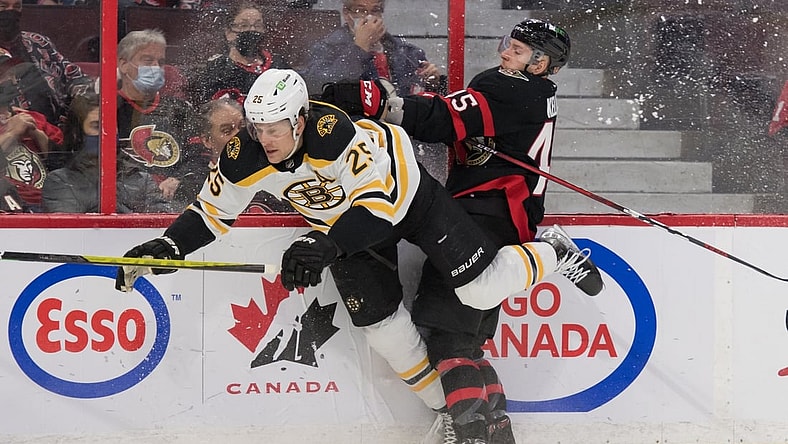 Feb 19, 2022; Ottawa, Ontario, CAN; Boston Bruins defenseman Brandon Carlo (25) is checked by Ottawa Senators left wing Parker Kelly (45) in the second period at the Canadian Tire Centre. Mandatory Credit: Marc DesRosiers-USA TODAY Sports
