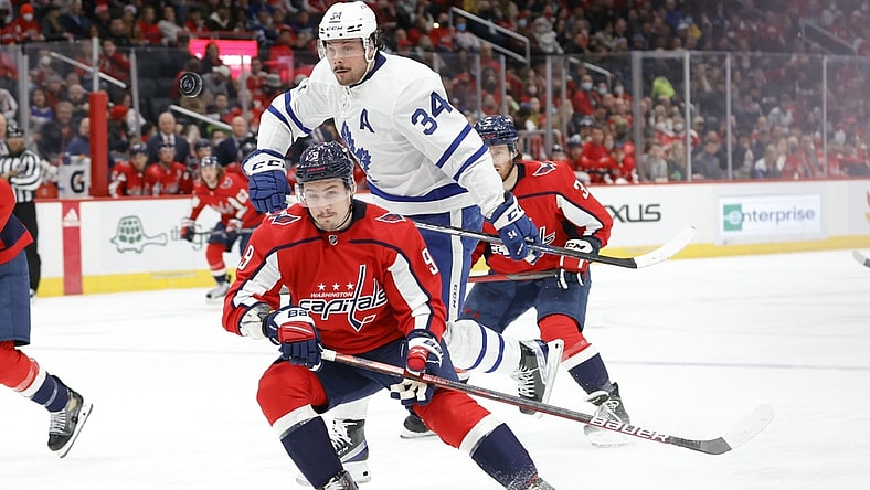 Feb 28, 2022; Washington, District of Columbia, USA; Toronto Maple Leafs center Auston Matthews (34) leaps around the check of Washington Capitals defenseman Dmitry Orlov (9) while chasing the puck in the second period at Capital One Arena. Mandatory Credit: Geoff Burke-USA TODAY Sports