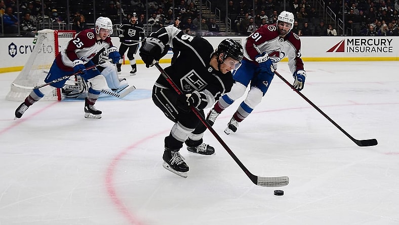 Mar 15, 2022; Los Angeles, California, USA; Los Angeles Kings center Blake Lizotte (46) moves the puck against Colorado Avalanche right wing Logan O'Connor (25) and center Nazem Kadri (91) during the third period at Crypto.com Arena. Mandatory Credit: Gary A. Vasquez-USA TODAY Sports