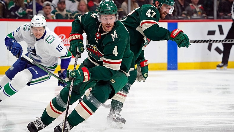Mar 24, 2022; Saint Paul, Minnesota, USA; Minnesota Wild defenseman Jon Merrill (4) controls the puck against the Vancouver Canucks at Xcel Energy Center. Mandatory Credit: Nick Wosika-USA TODAY Sports
