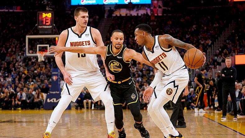 Apr 16, 2022; San Francisco, California, USA; Golden State Warriors guard Stephen Curry (30) reaches past Denver Nuggets center Nikola Jokic (15) to pressure guard Monte Morris (11) in the first quarter during game one of the first round for the 2022 NBA playoffs at the Chase Center. Mandatory Credit: Cary Edmondson-USA TODAY Sports