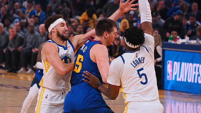 Apr 18, 2022; San Francisco, California, USA; Golden State Warriors guard Klay Thompson (11) and forward Kevon Looney (5) defend Denver Nuggets center Nikola Jokic (15) during the first quarter of game two of the first round for the 2022 NBA playoffs at Chase Center. Mandatory Credit: Kelley L Cox-USA TODAY Sports