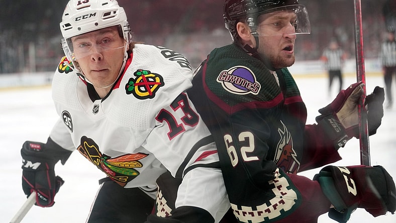 Apr 20, 2022; Glendale, Arizona, USA; Chicago Blackhawks center Henrik Borgstrom (13) and Arizona Coyotes defenseman J.J. Moser (62) battle for position during the first period at Gila River Arena. Mandatory Credit: Joe Camporeale-USA TODAY Sports
