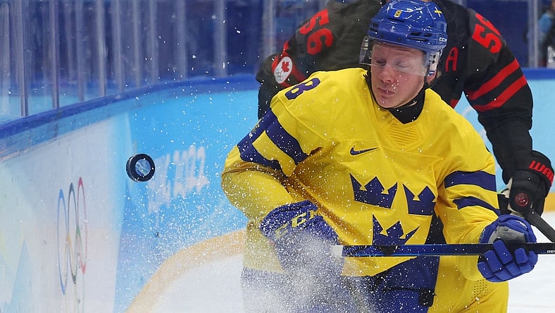 Feb 16, 2022; Beijing, China; Fredrik Olofsson of Sweden in action with Maxim Noreau of Canada in a men's ice hockey quarterfinal match during the Beijing 2022 Olympic Winter Games at National Indoor Stadium. Mandatory Credit: Brian Snyder/Reuters via USA TODAY Sports