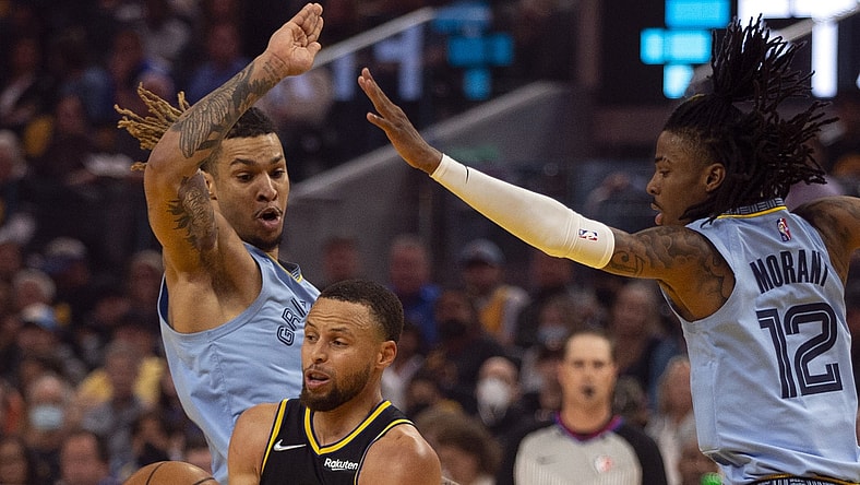 May 7, 2022; San Francisco, California, USA; Golden State Warriors guard Stephen Curry (30) drives between Memphis Grizzlies forward Brandon Clarke (15) and guard Ja Morant (12) during the first half of game three of the second round for the 2022 NBA playoffs at Chase Center. Mandatory Credit: D. Ross Cameron-USA TODAY Sports
