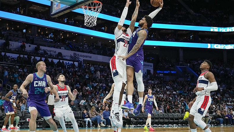 Apr 10, 2022; Charlotte, North Carolina, USA; Charlotte Hornets forward Miles Bridges (0) goes for the dunk defended by Washington Wizards center Daniel Gafford (21) during the second half at Spectrum Center. Mandatory Credit: Jim Dedmon-USA TODAY Sports