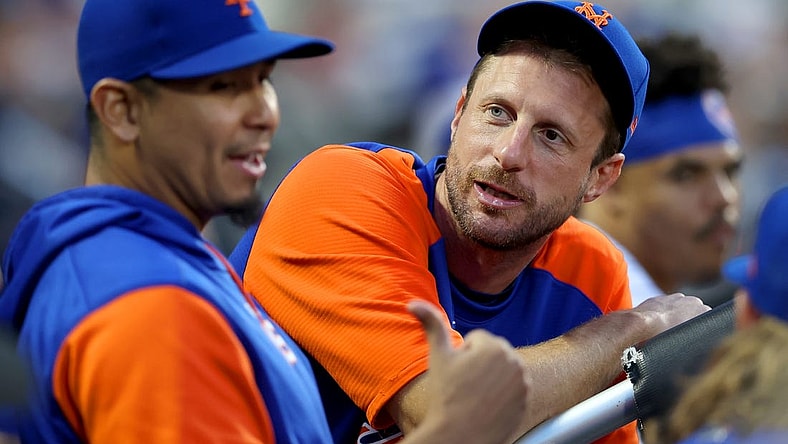 Jun 15, 2022; New York City, New York, USA; New York Mets injured pitcher Max Scherzer (21) talks to starting pitcher Carlos Carrasco (59) in the dugout during the third inning against the Milwaukee Brewers at Citi Field. Mandatory Credit: Brad Penner-USA TODAY Sports
