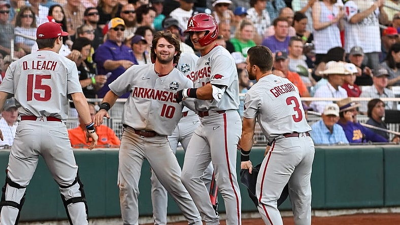 Jun 21, 2022; Omaha, NE, USA;  Arkansas Razorbacks right fielder Chris Lanzilli (18) greets catcher Dylan Leach (15) and first baseman Peyton Stovall (10)  and left fielder Zack Gregory (3) after hitting a home run against the Auburn Tigers in the fourth inning at Charles Schwab Field. Mandatory Credit: Steven Branscombe-USA TODAY Sports
