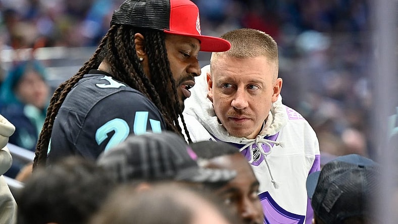 Apr 18, 2022; Seattle, Washington, USA; Former NFL running back Marshawn Lynch and musician Macklemore talk during the game between the Seattle Kraken and the Ottawa Senators at Climate Seattle defeated Ottawa 4-2. Pledge Arena. Mandatory Credit: Steven Bisig-USA TODAY Sports