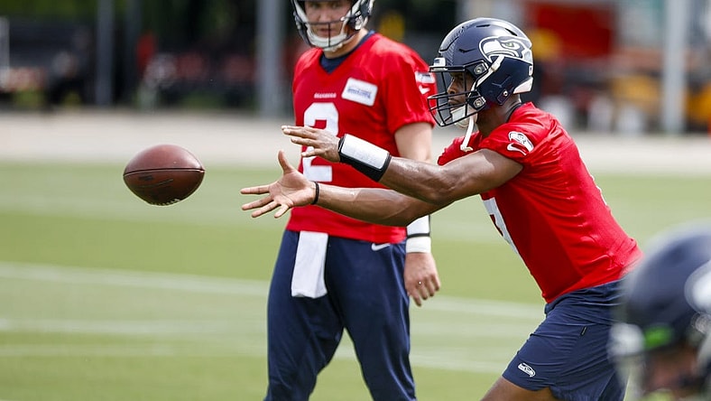 Jun 7, 2022; Renton, Washington, USA; Seattle Seahawks quarterback Geno Smith (7) receives a shotgun snap in front of quarterback Drew Lock (2) during minicamp practice at the Virginia Mason Athletic Center Field. Mandatory Credit: Joe Nicholson-USA TODAY Sports
