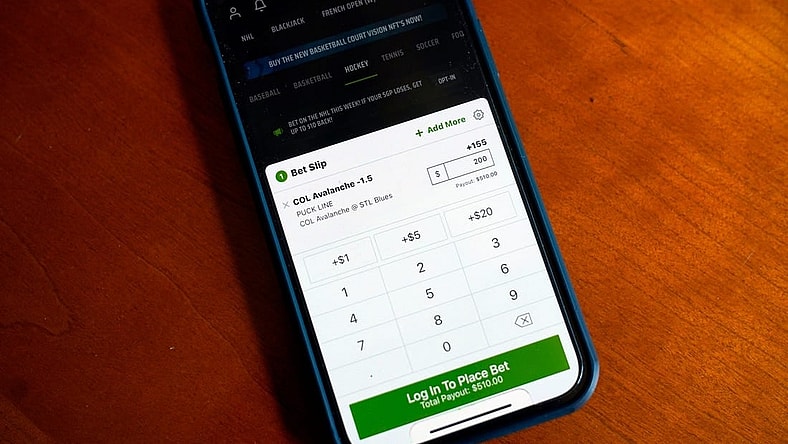 Photo illustration of the Draft Kings app on an iPhone.

News Online Sports Betting Project