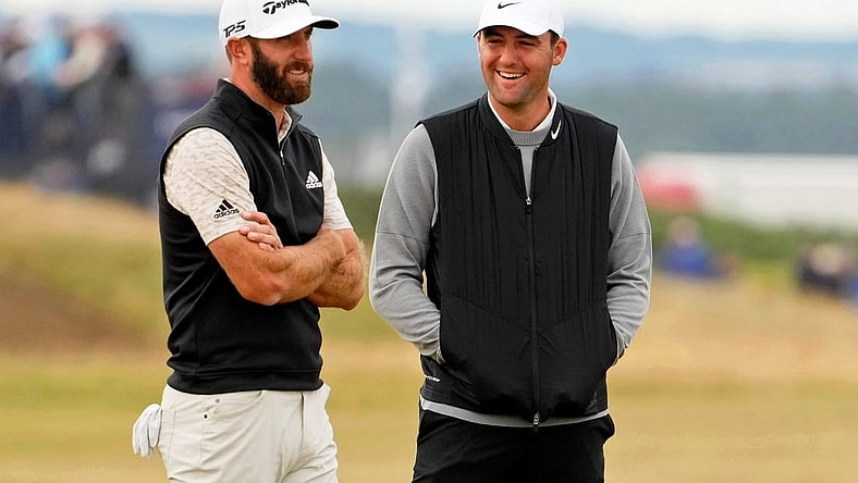 Jul 14, 2022; St. Andrews, SCT; Dustin Johnson (left) talks with Scottie Scheffler during a delay on the 14th hole during the first round of the 150th Open Championship golf tournament at St. Andrews Old Course. Mandatory Credit: Rob Schumacher-USA TODAY Sports