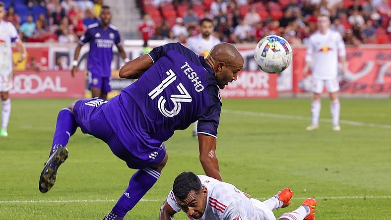 Aug 13, 2022; Harrison, New Jersey, USA; Orlando City SC forward Tesho Akindele (13) heads the ball over New York Red Bulls midfielder Cristian Casseres Jr (23) during the second half at Red Bull Arena. Mandatory Credit: Vincent Carchietta-USA TODAY Sports