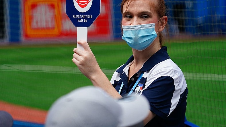 Aug 22, 2021; Toronto, Ontario, CAN; A Toronto Blue Jays stadium attendant holds up a sign reminding fans to wear their masks during a game against the Detroit Tigers at Rogers Centre. Mandatory Credit: John E. Sokolowski-USA TODAY Sports