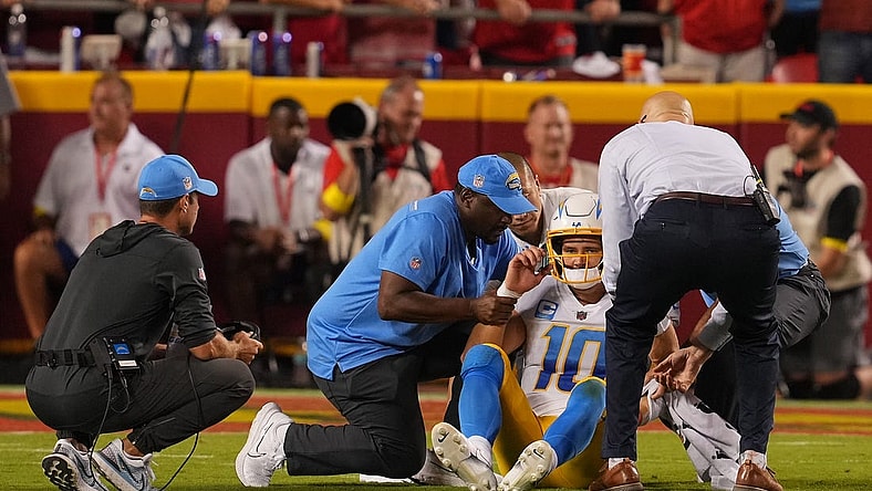 Sep 15, 2022; Kansas City, Missouri, USA; Los Angeles Chargers quarterback Justin Herbert (10) is looked at by team trainers after being hit by Kansas City Chiefs defensive end Mike Danna (51) during the second half at GEHA Field at Arrowhead Stadium. Mandatory Credit: Jay Biggerstaff-USA TODAY Sports